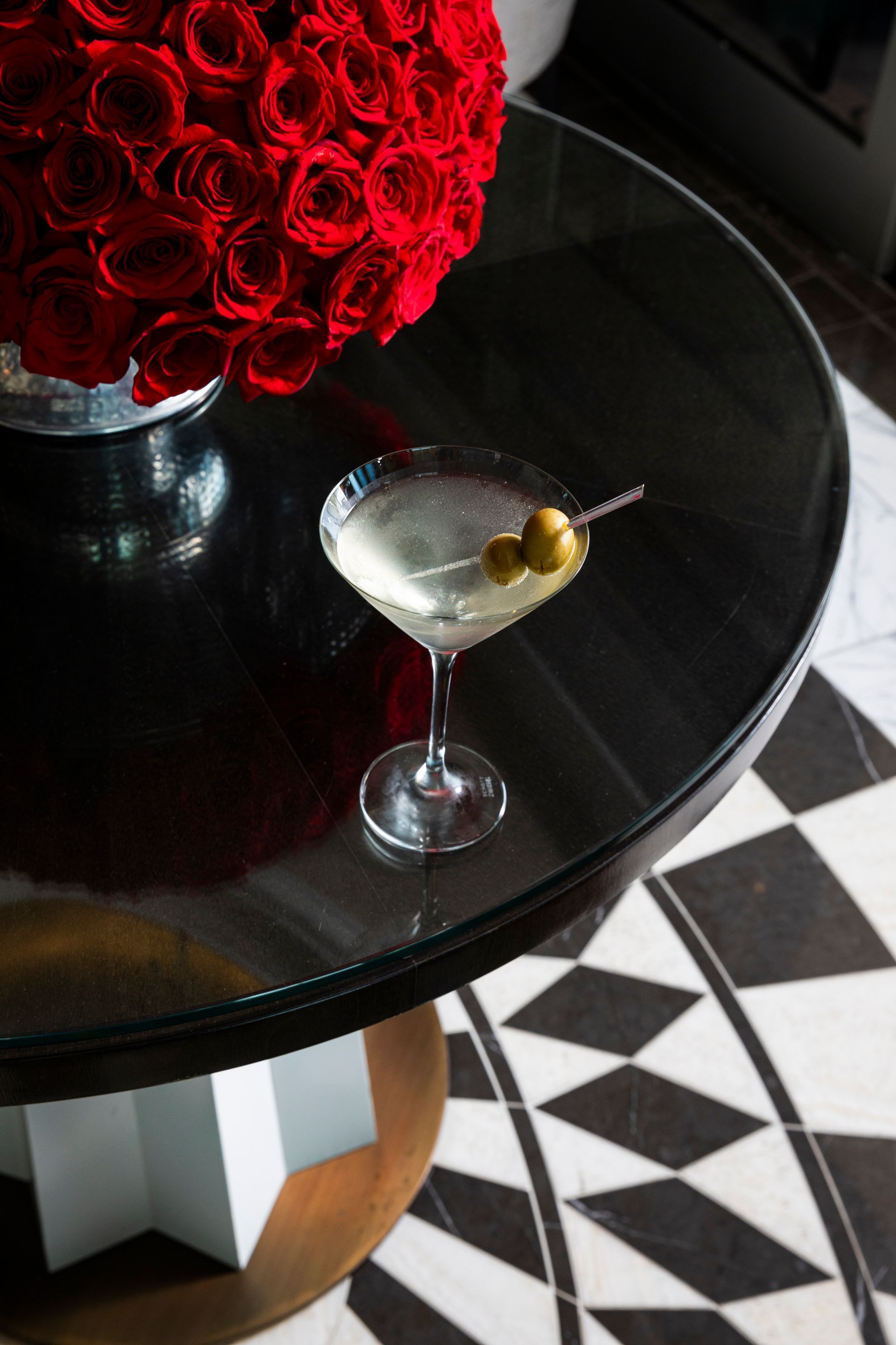 Martini Glass over Checkered floors next to Red roses