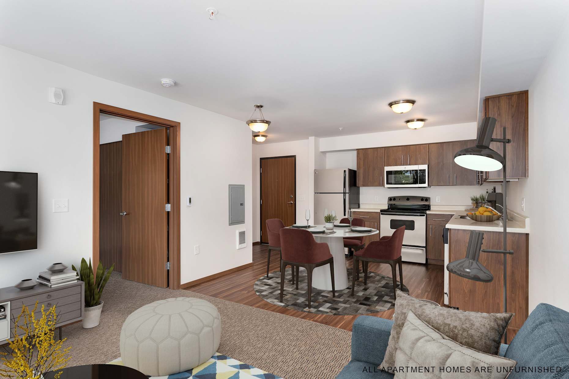 Open-concept living space with kitchen, dining, and living areas. Brown cabinets, white appliances, and a blue couch.