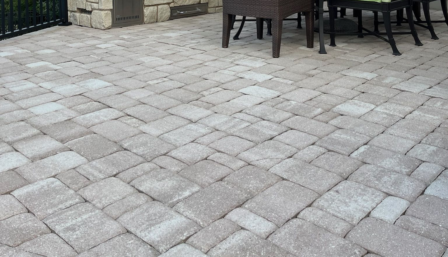 Stone patio with gray pavers and outdoor dining chairs and table at the edge.