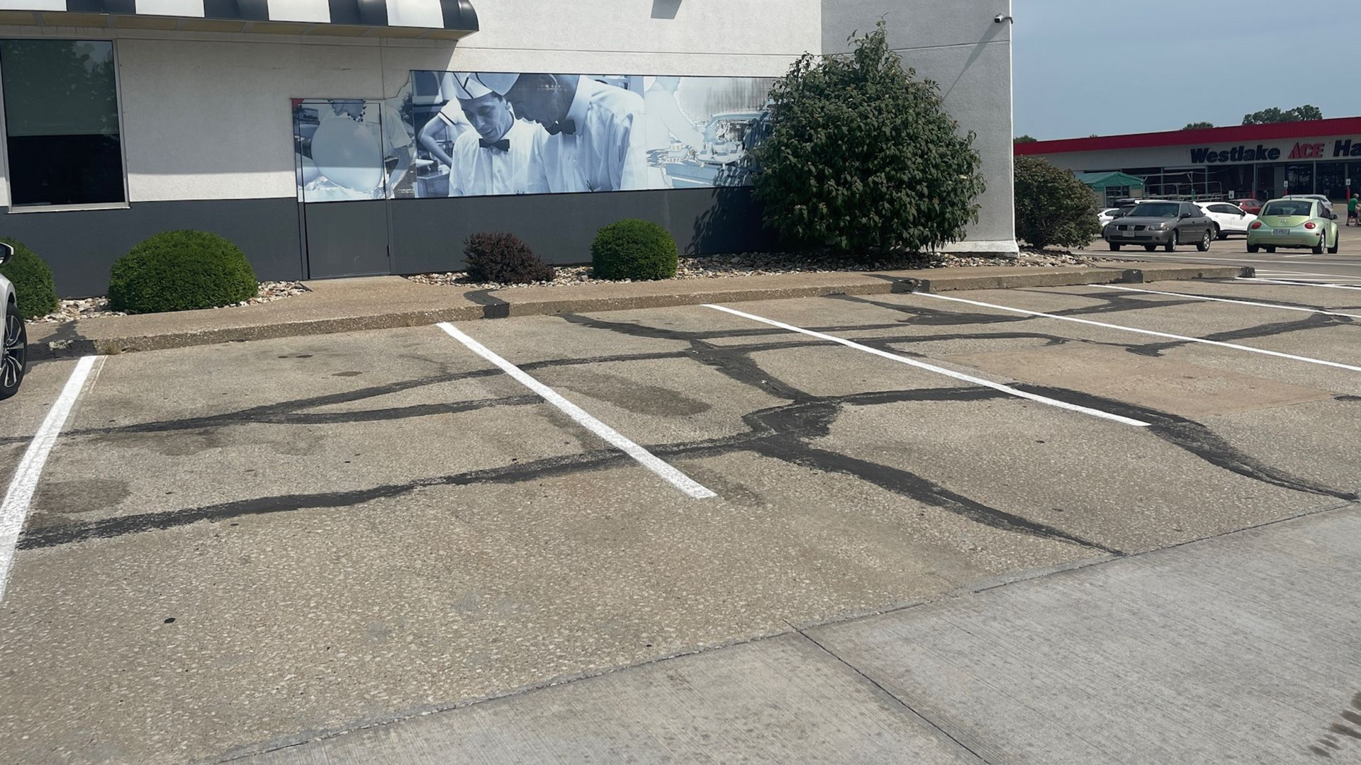 Empty accessible parking spaces with white markings outside a building, beside a drive-through lane.