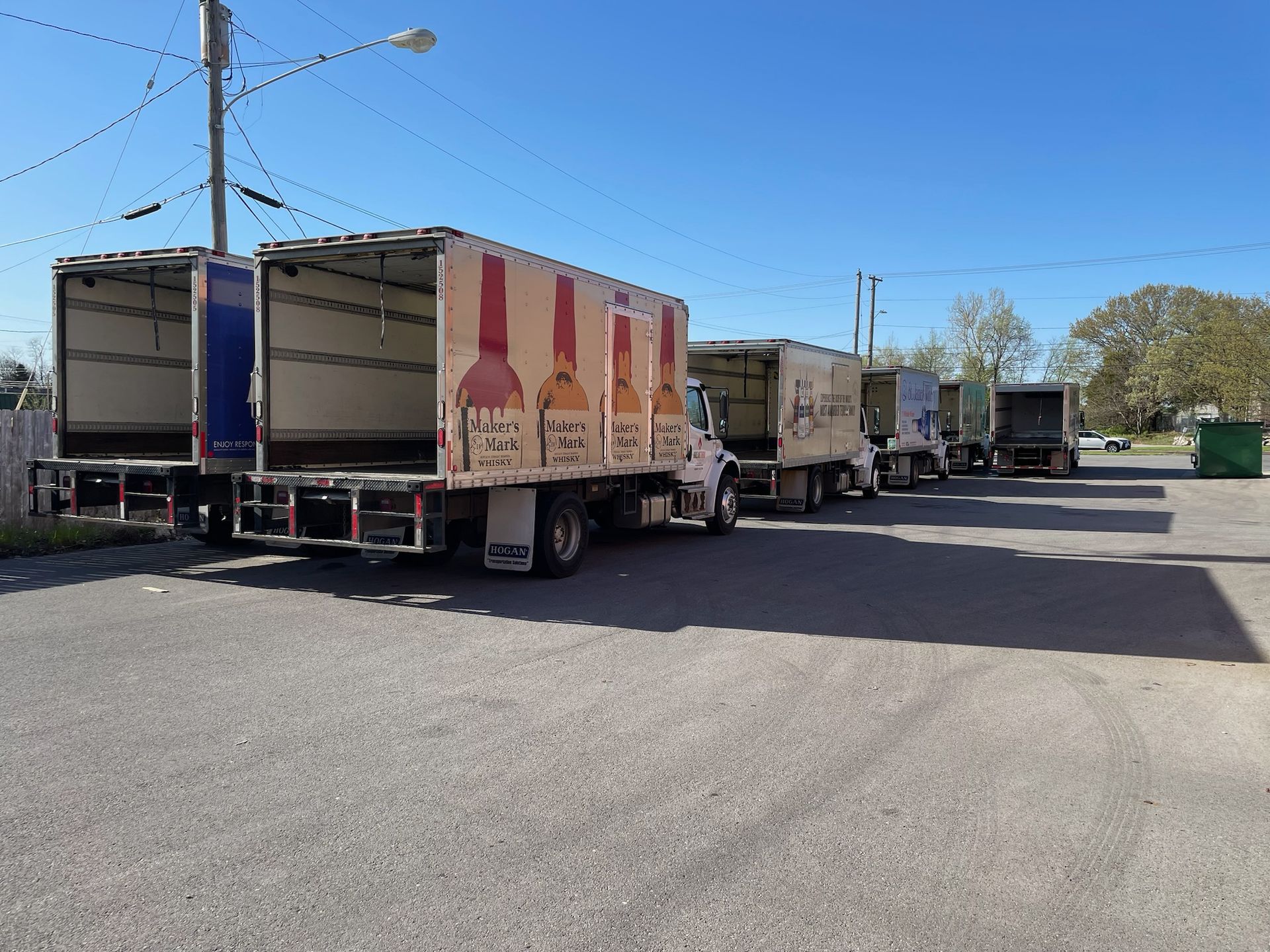 Parked delivery trucks lined up in a sunny lot with a blue sky overhead