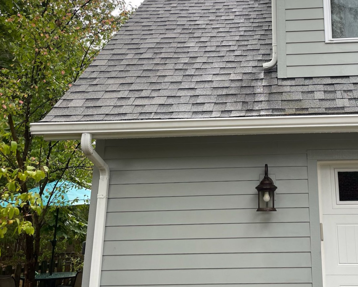 Gray house exterior with shingled roof, white trim, lantern, and partial front door