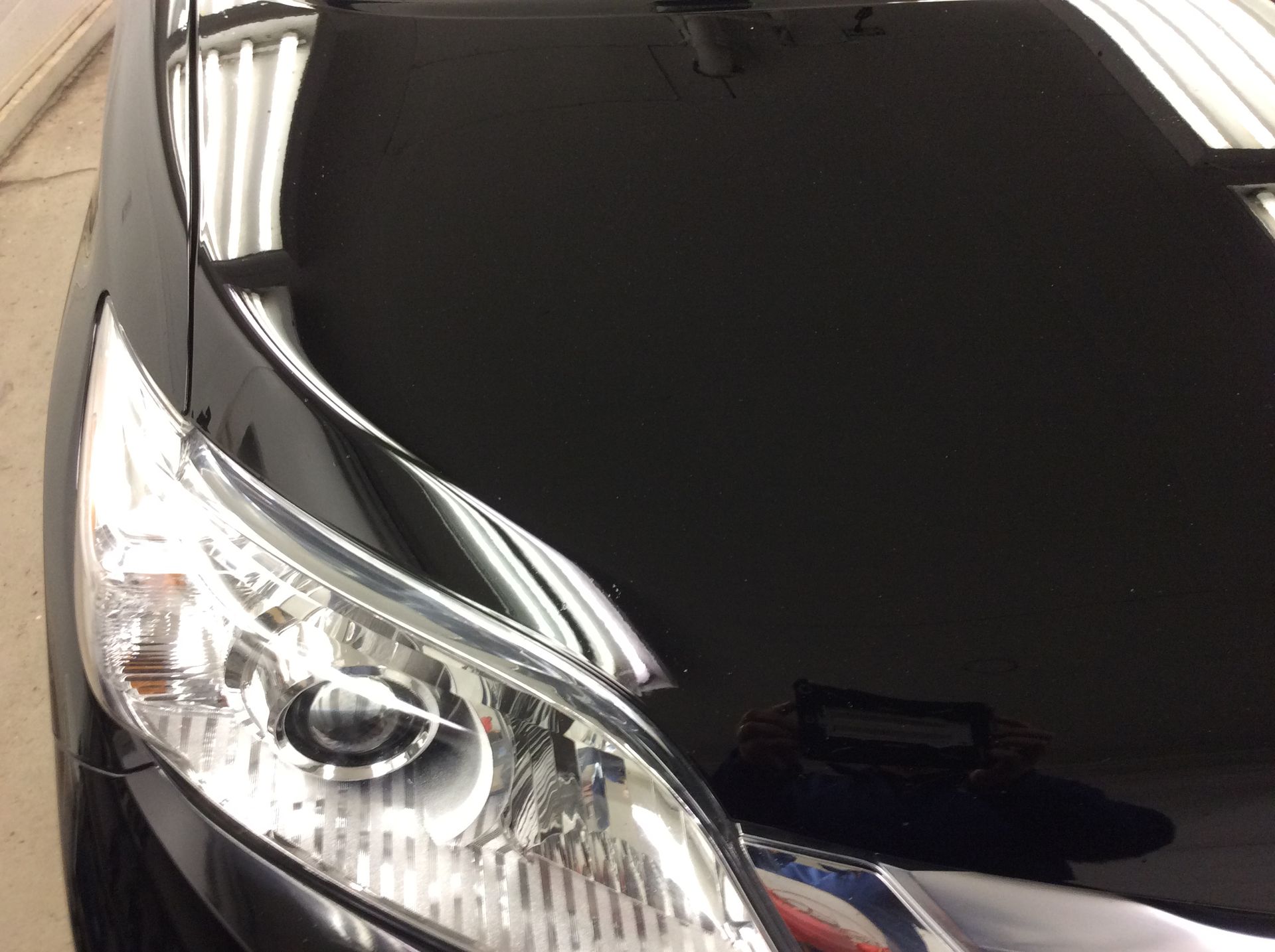 A close up of a black car 's headlight and hood