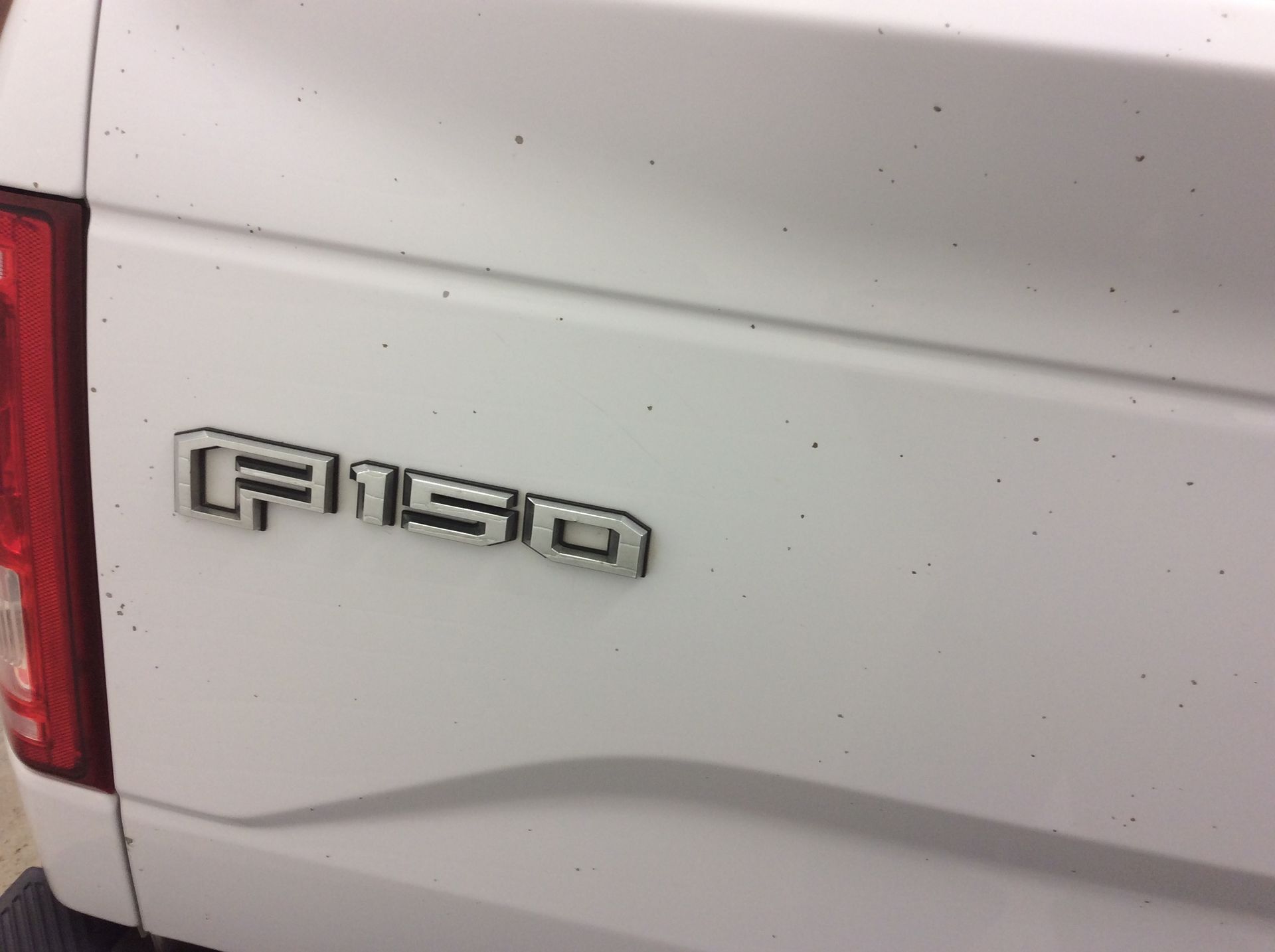 A white ford f150 truck is parked in a garage.