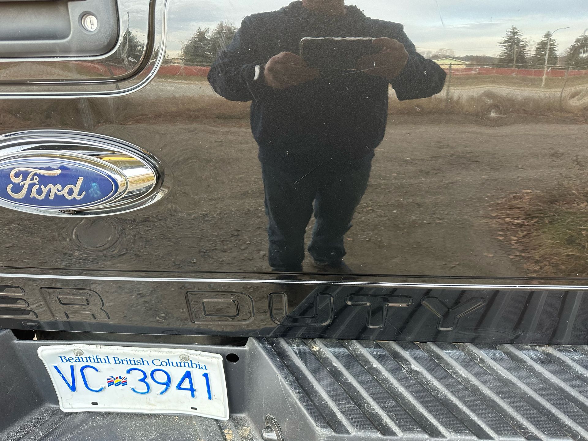 A man is taking a picture of himself in the back of a ford truck