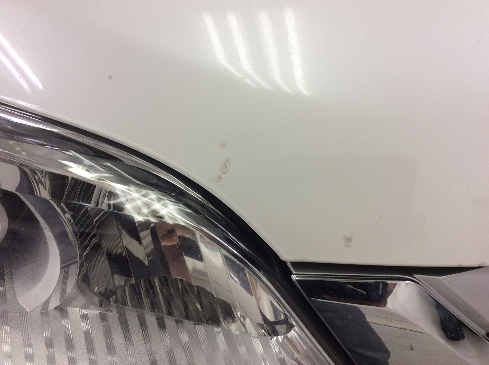 A close up of a white car hood and headlight