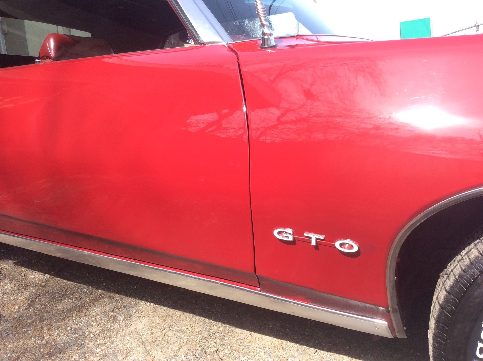 A red gto car is parked on a gravel road