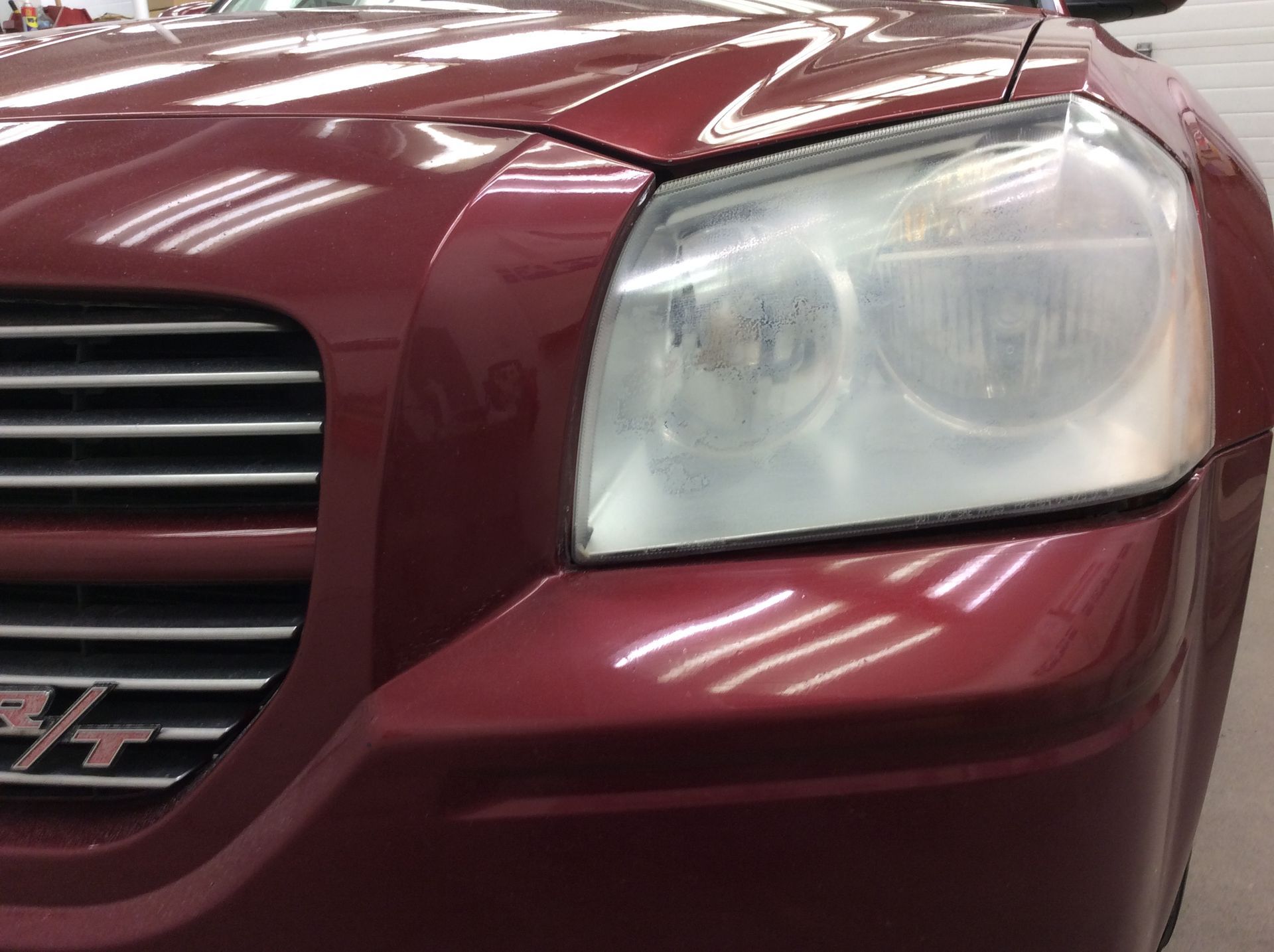 A close up of a red car 's headlight and grille