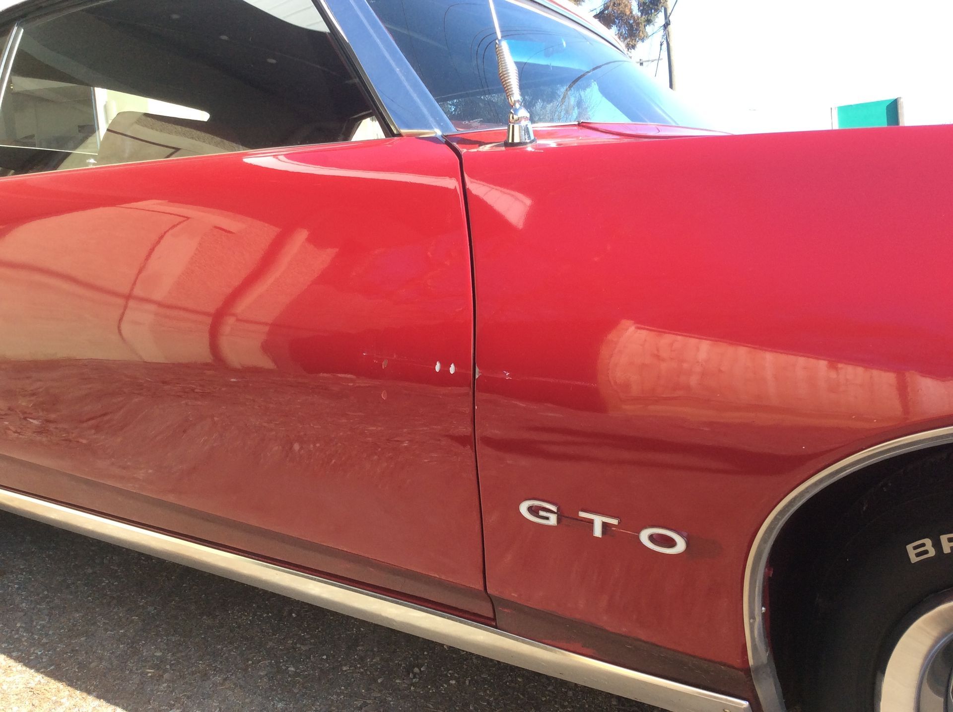 A red gto car is parked on the side of the road.