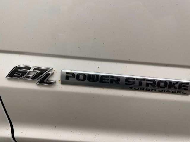 The emblem on the side of a white truck says 6.7l power stroke turbo diesel.