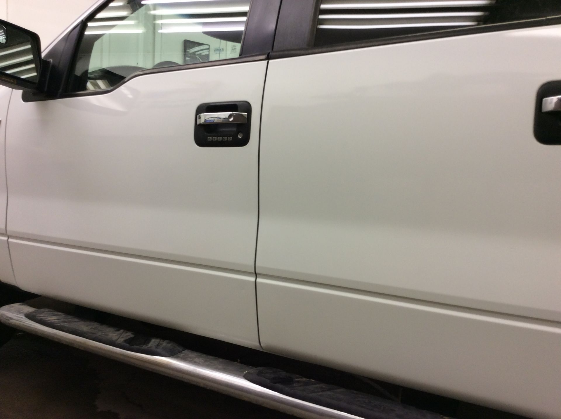 A white truck with black handles is parked in a garage.