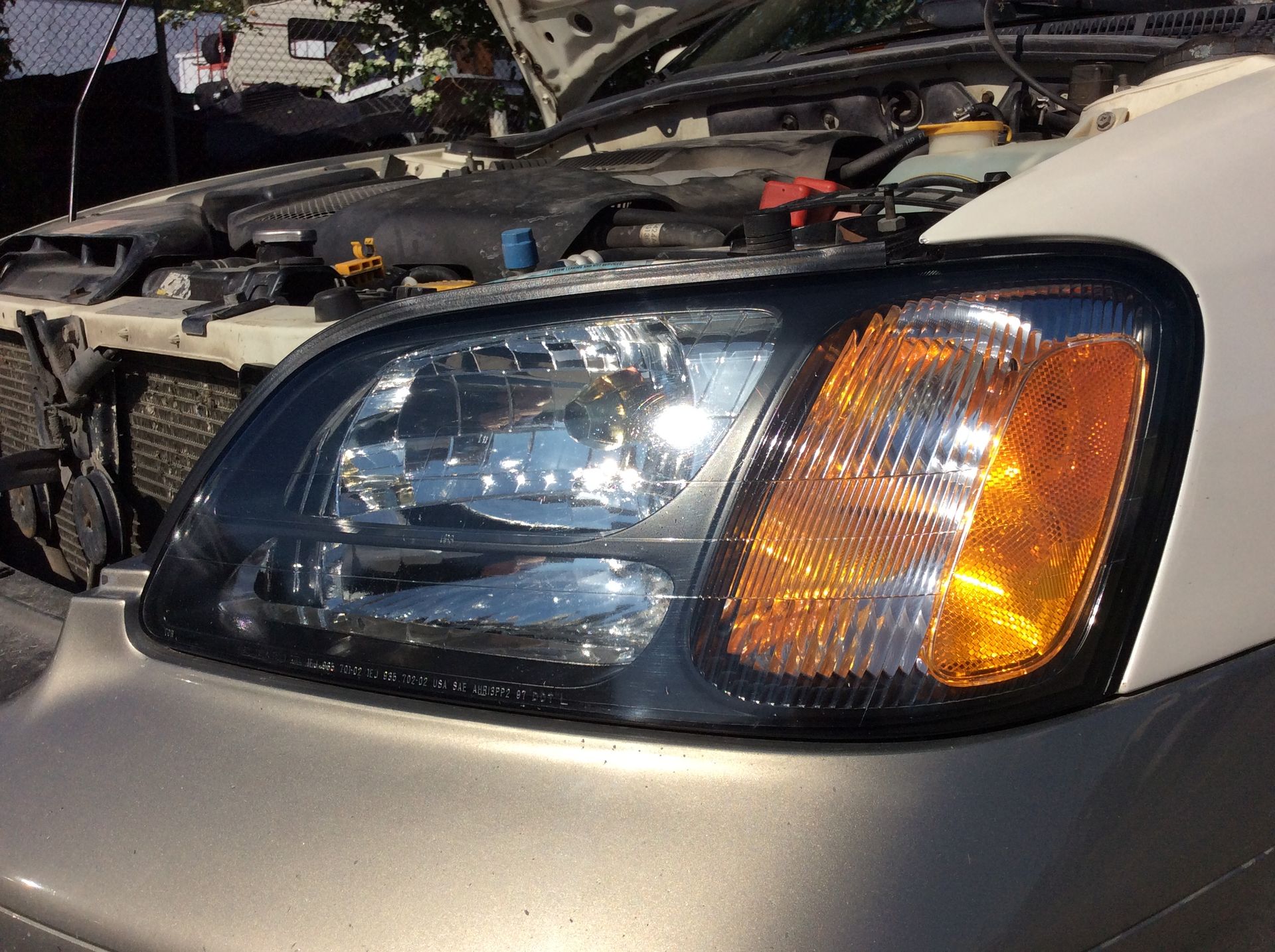 A close up of a car 's headlight with the hood open