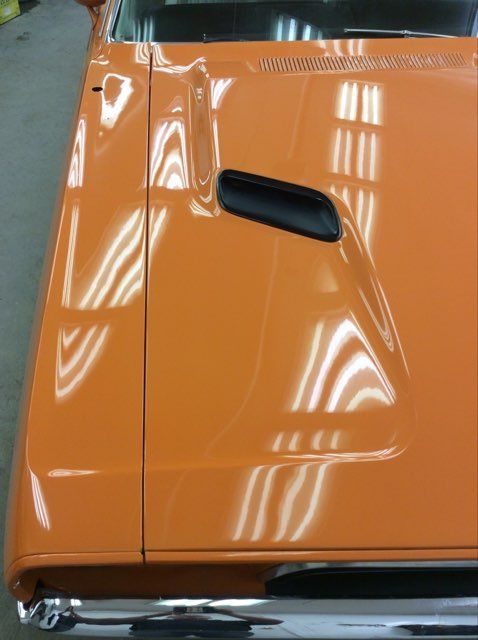 A close up of the hood of an orange car