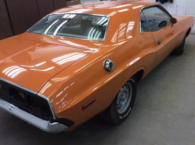 An orange dodge challenger is parked in a garage