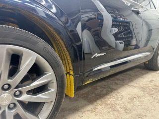 A black car with a continental tire is parked in a garage.
