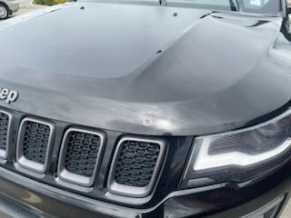 A black jeep compass is parked in a parking lot.