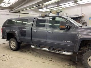 A gray truck with a canopy is parked in a garage.