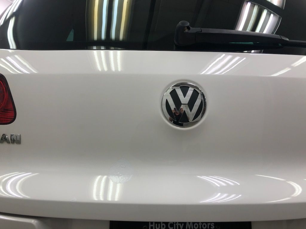 The back of a white volkswagen with a logo on it.