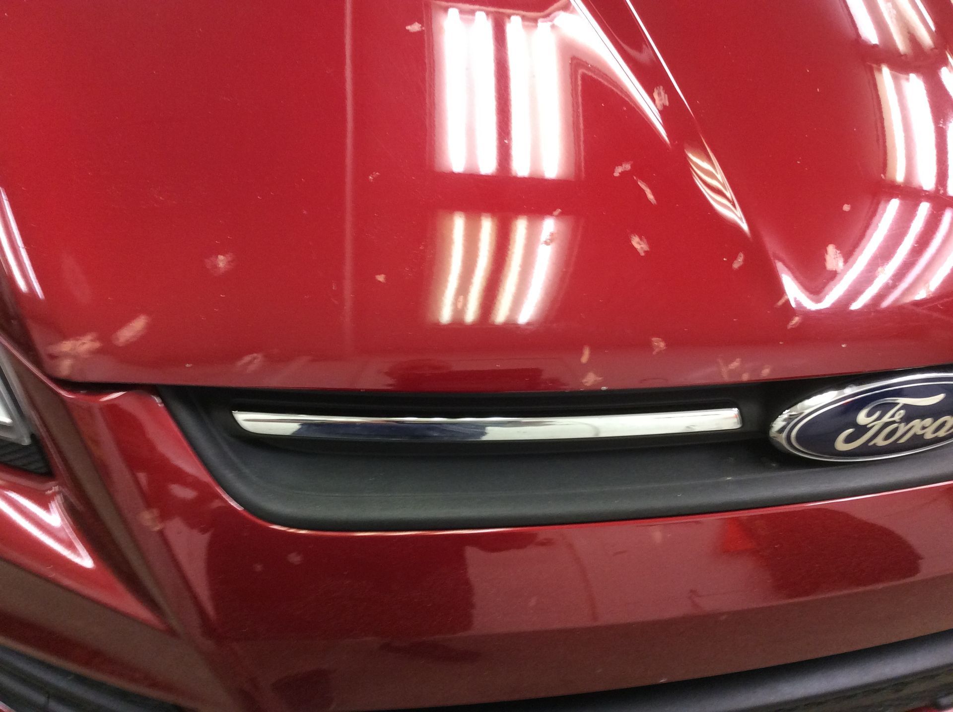 A red ford car is parked in a garage
