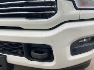 A close up of a white truck 's front bumper with a tow hook.