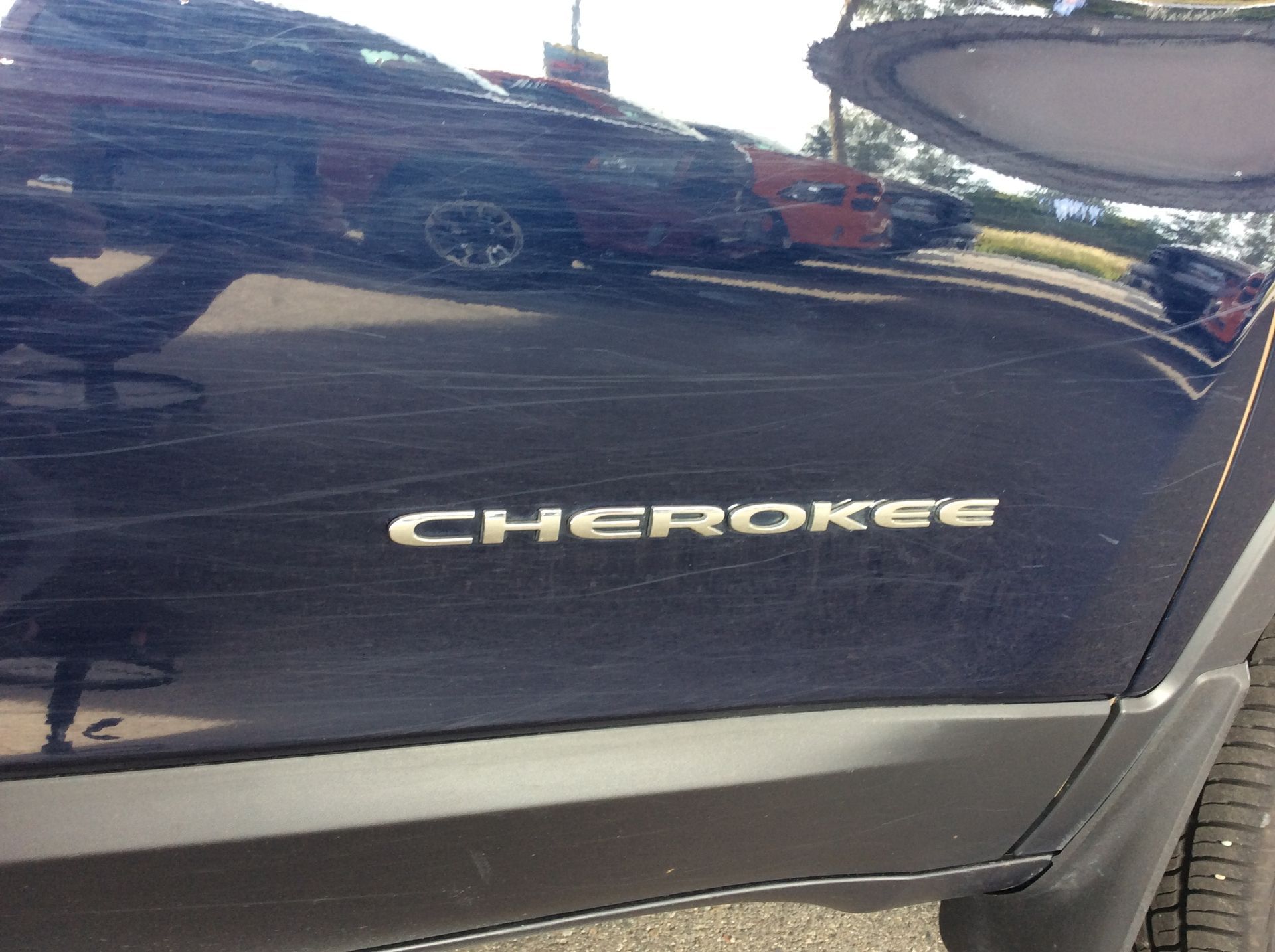 A black jeep cherokee is parked in a parking lot