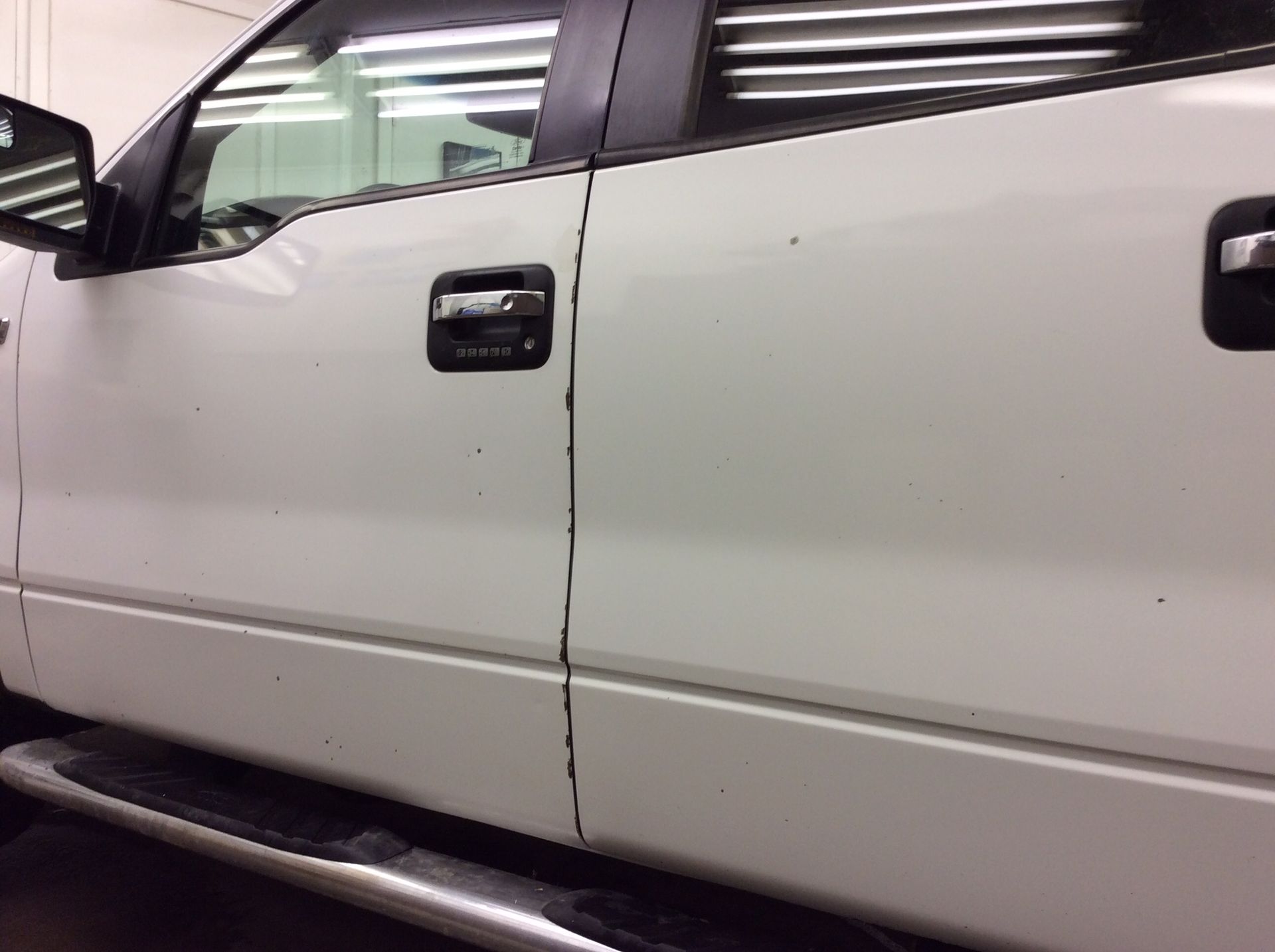 A white truck with black handles is parked in a garage.
