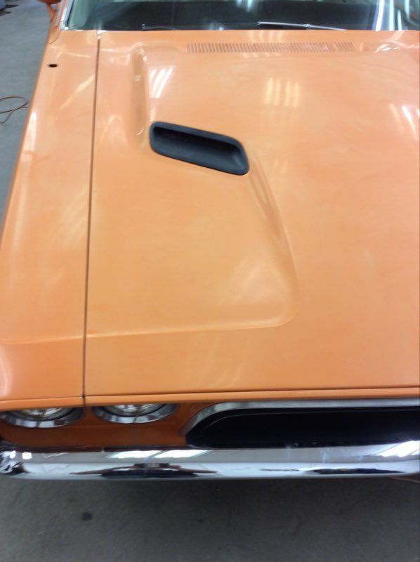 A close up of the hood of an orange car