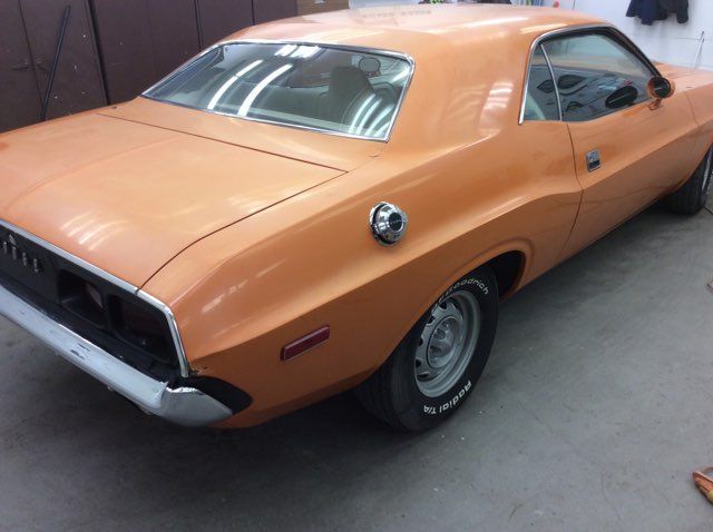 An orange dodge challenger is parked in a garage