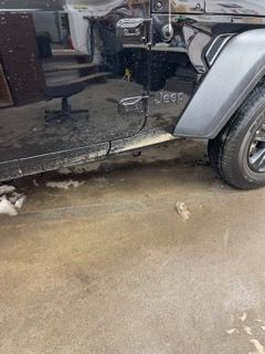 A jeep is parked in a garage next to a chair.