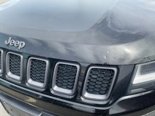 A black jeep compass is parked on the side of the road.