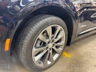 A close up of a black car with a tire on the ground.
