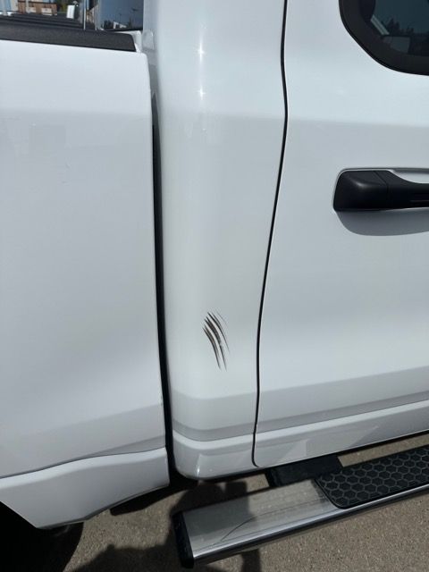 A white truck has a scratch on the side of it