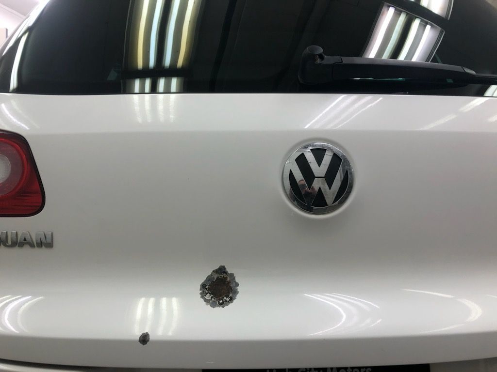The back of a white volkswagen with a black logo on it