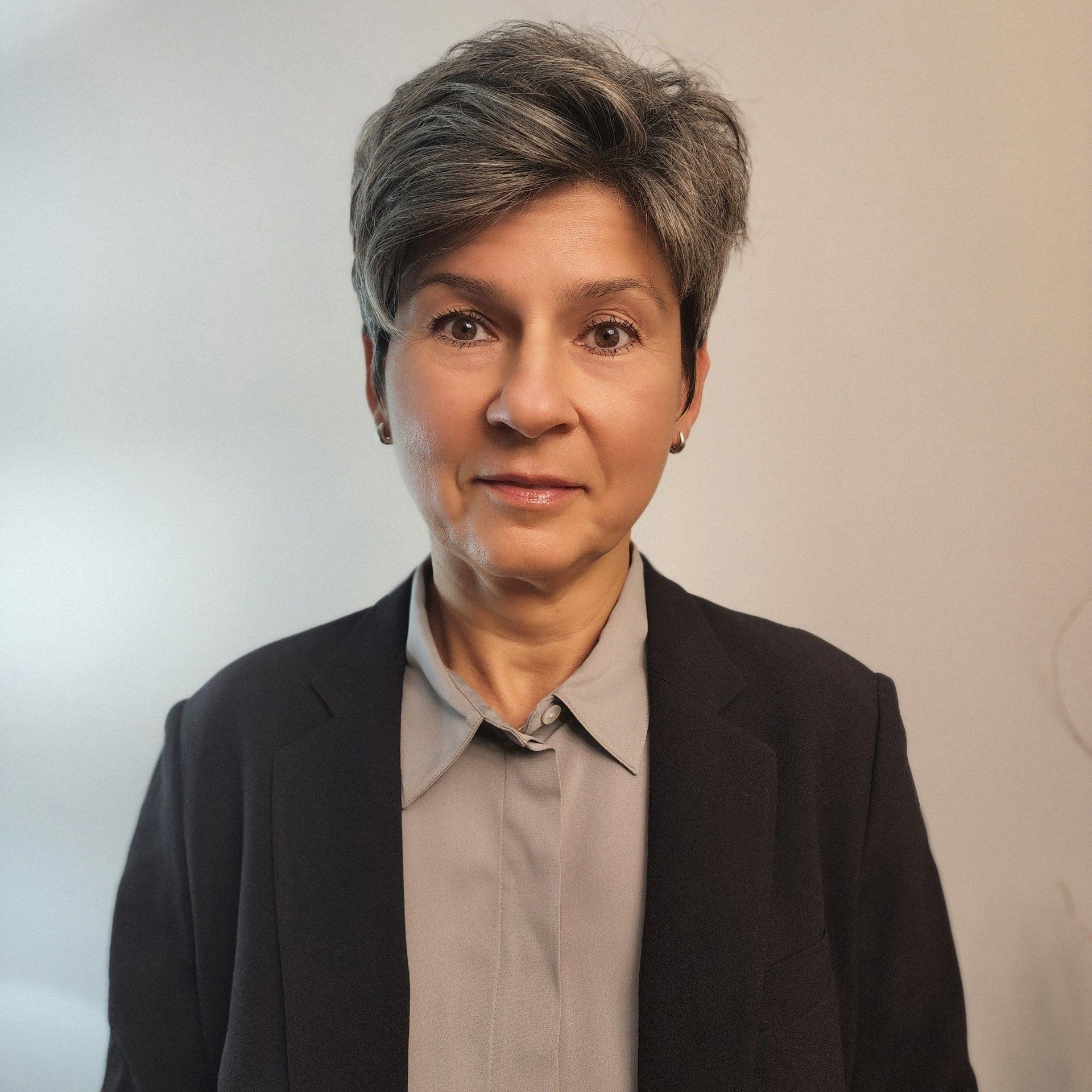 A woman with gray hair is wearing a black jacket and a grey shirt