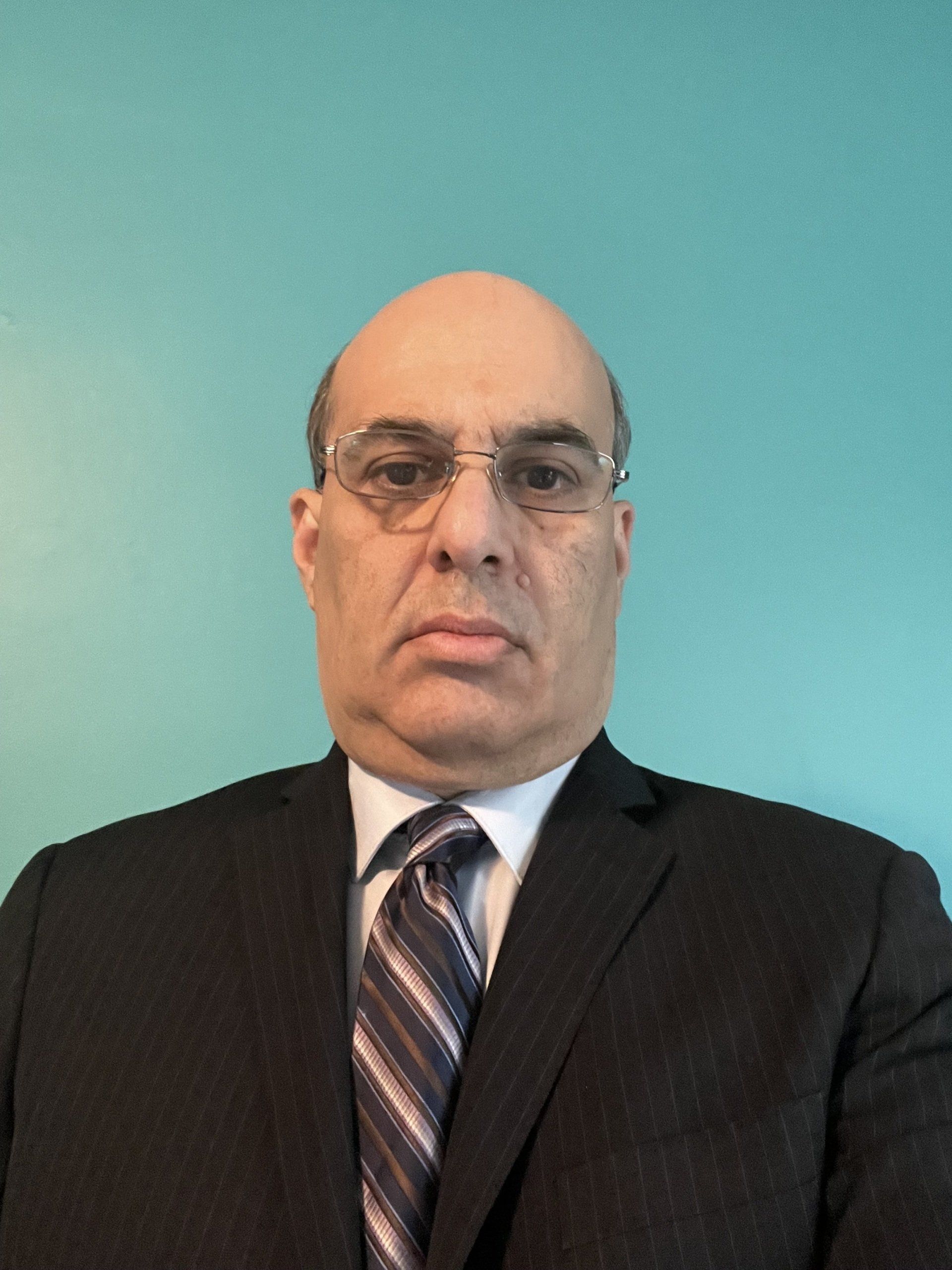 A man in a suit and tie is standing in front of a blue wall