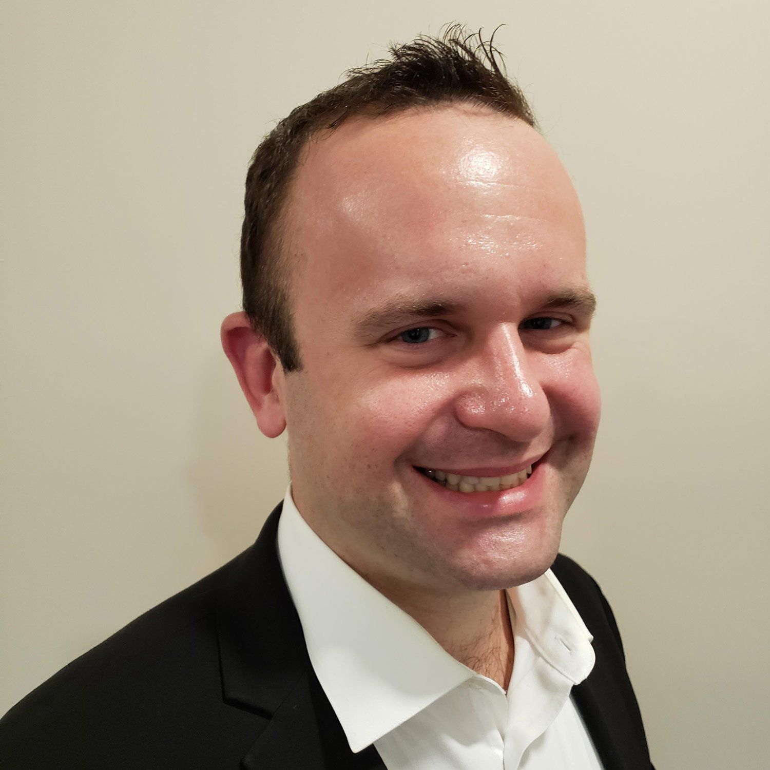 A man in a suit and white shirt is smiling for the camera