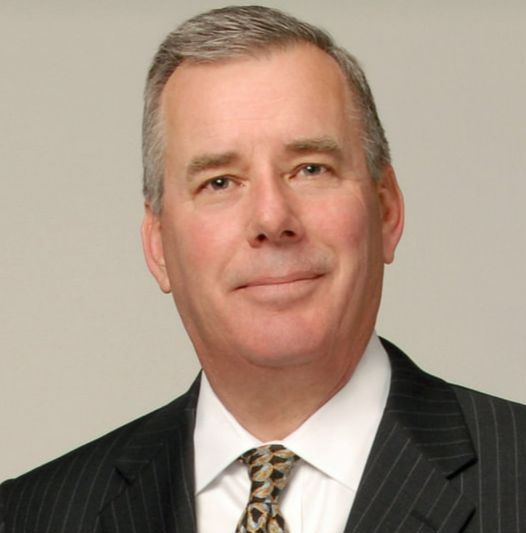 A man in a suit and tie is smiling for the camera