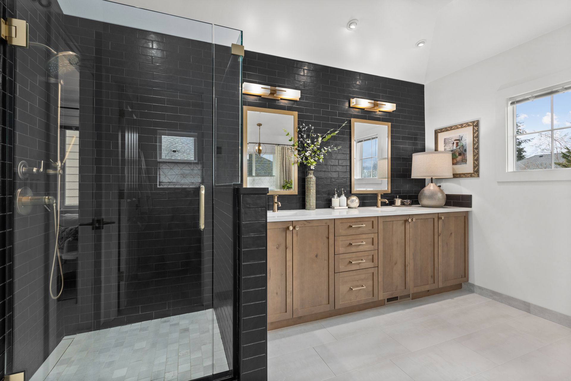 Modern bathroom with black tiled shower, double vanity, and large mirrors