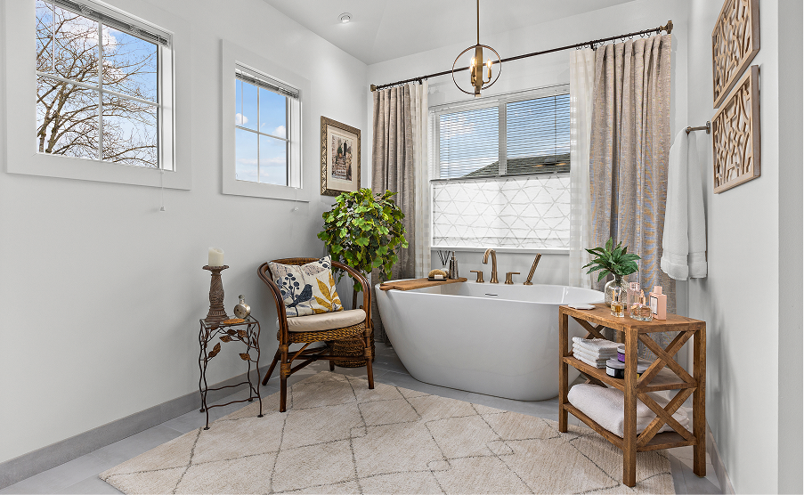 Bright bathroom with soaking tub, white tile, and a cozy chair by the window