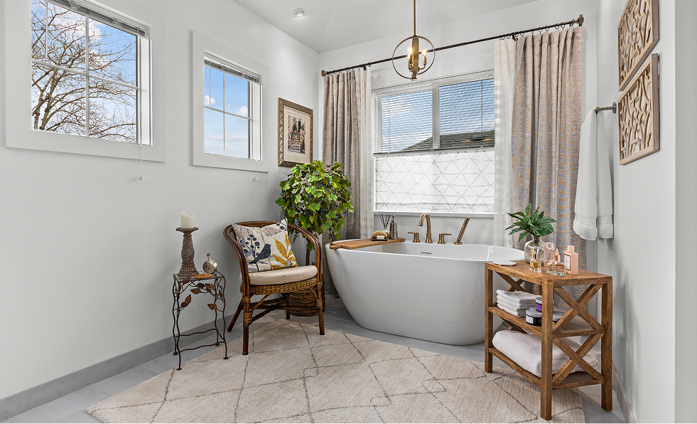 Bright bathroom with a freestanding tub, large window, plants, and light tile floor