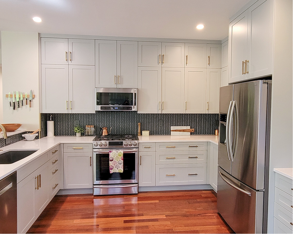 Modern white kitchen with stainless steel appliances, dark backsplash, and hardwood floors