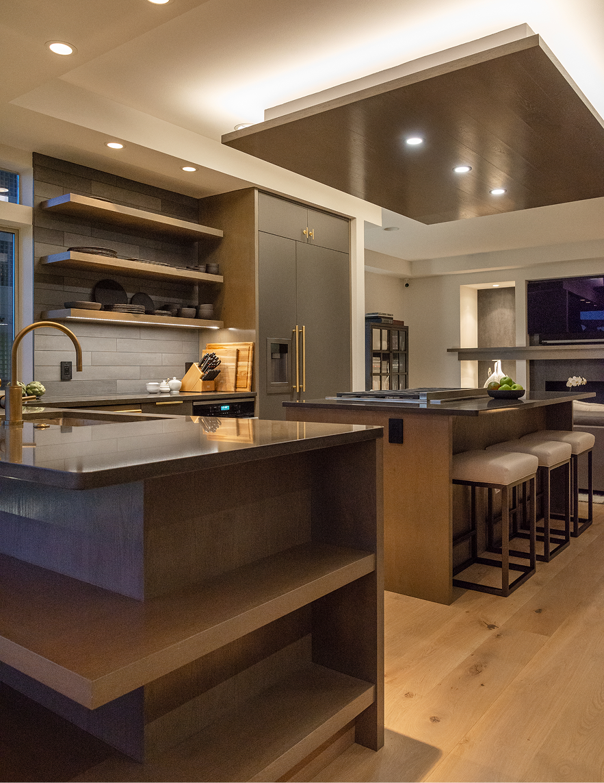 Modern kitchen interior with dark wood cabinets, island seating, and warm recessed lighting