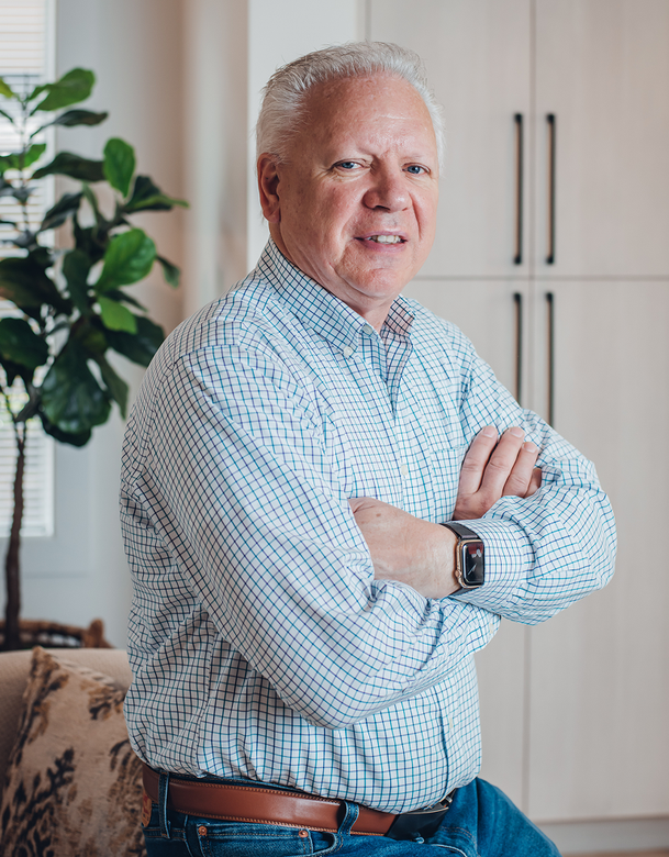 Bill Olson near a plant and cabinets
