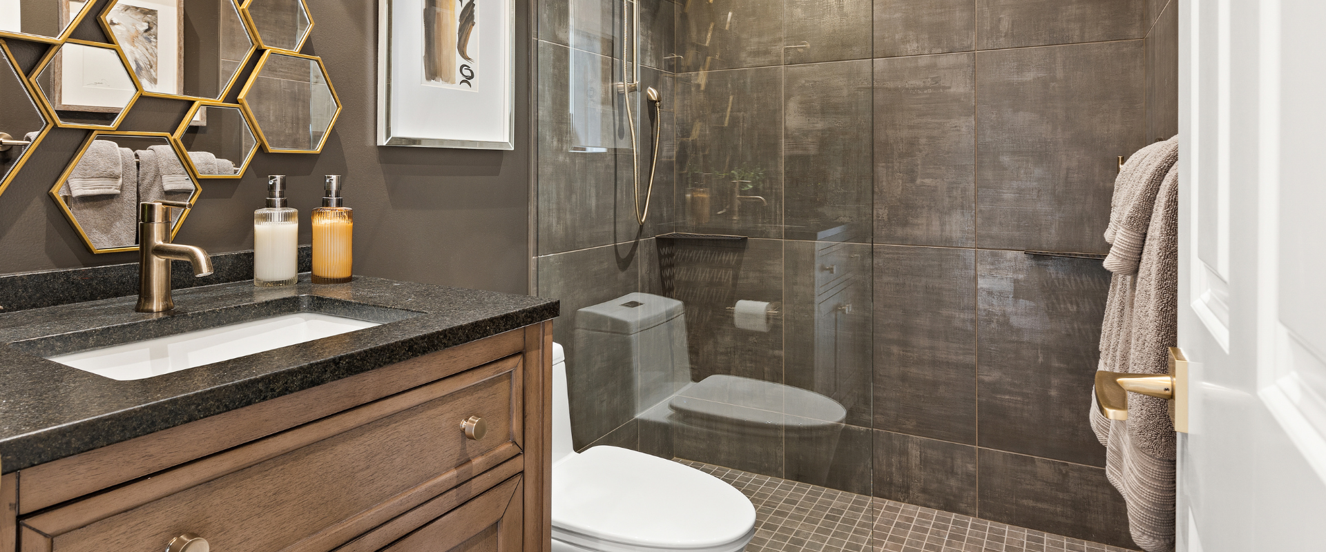 Modern bathroom with glass shower, hexagonal mirror, and marble sink vanity