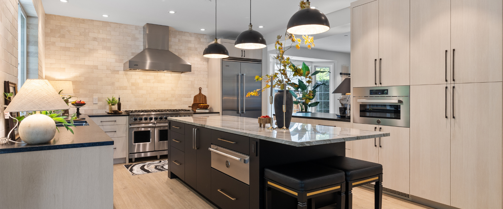 Modern kitchen with island, pendant lights, white cabinets, and stainless steel appliances