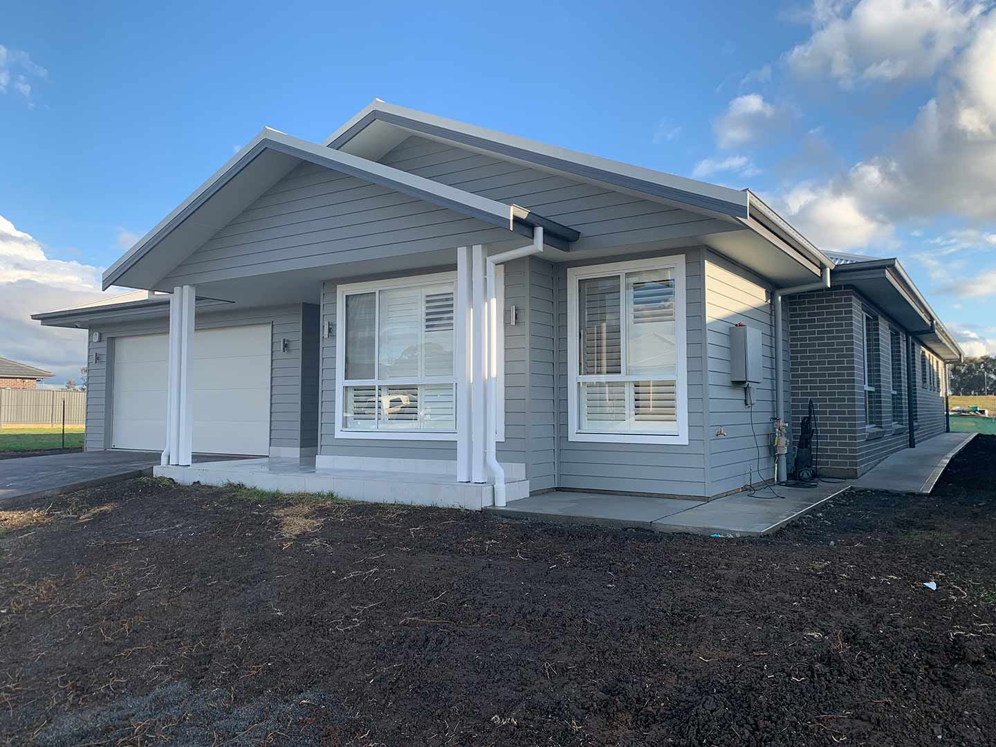 A Gray And White House With A Blue Sky In The Background — Morphett Construction In Calala, NSW