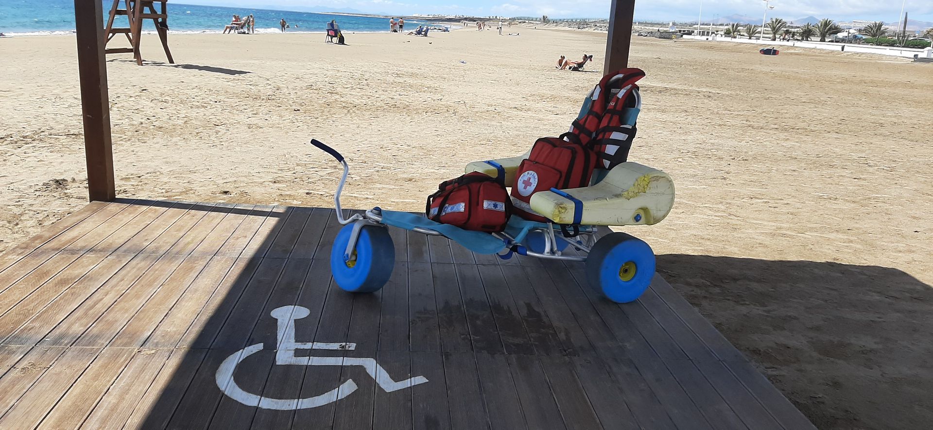 A wheelchair is parked in a handicapped parking spot on the beach.
