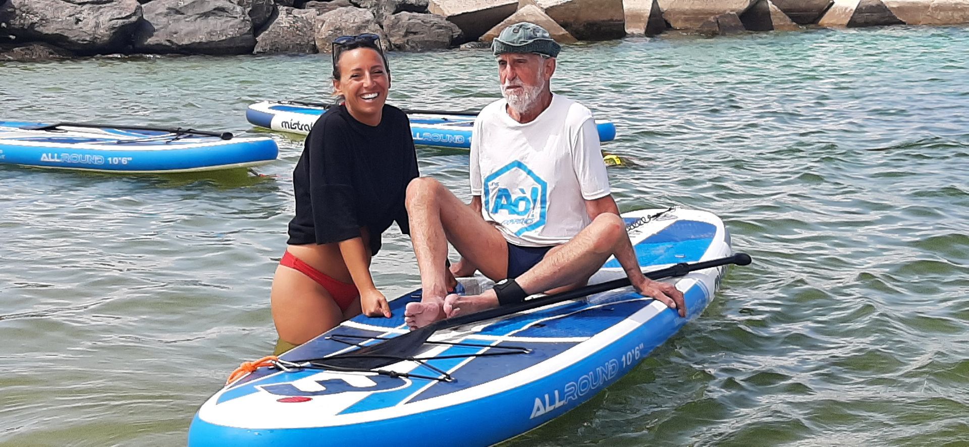 A man and a woman are sitting on a paddle board in the water.