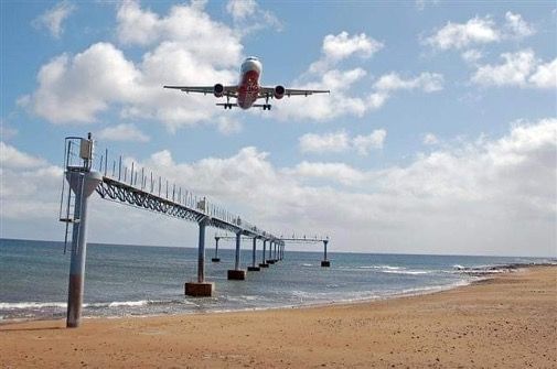 A plane is taking off from a pier over a beach.