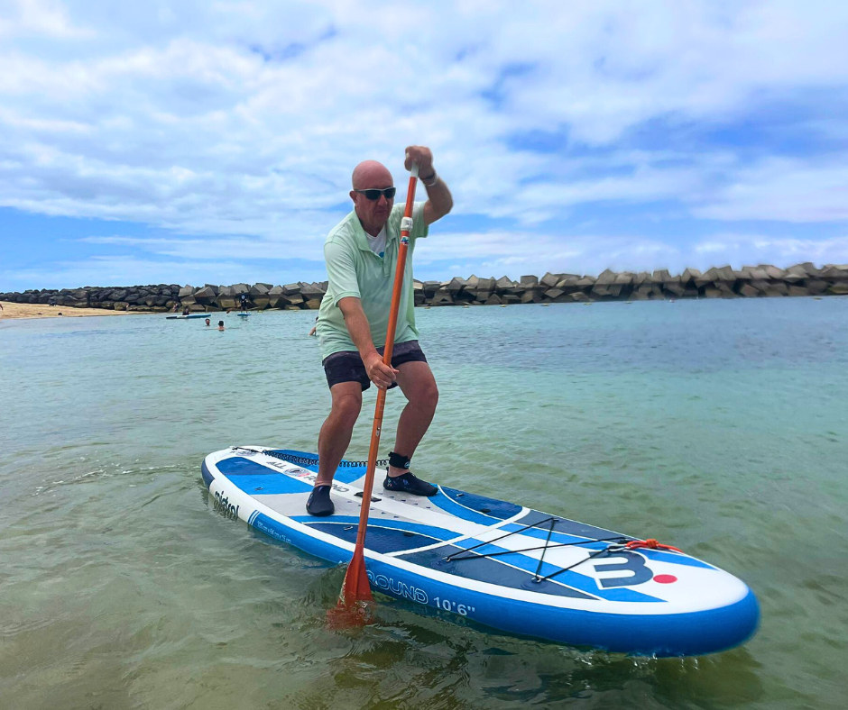 A man is riding a paddle board in the water.